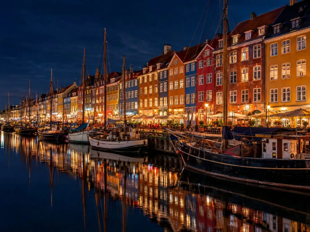 Die bemalten Häuser entlang Nyhavn, die sich nachts im Kanal spiegeln